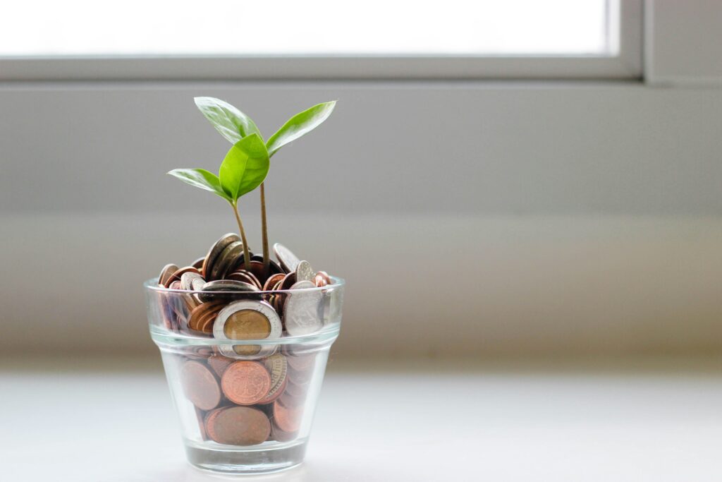 Jar of coins with sprouting plant representing financial growth.